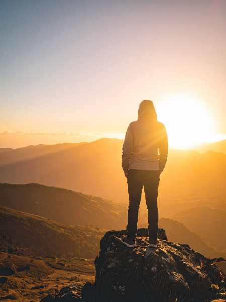 Man standing on a mountain overlooking a Los Angeles sunset, symbolizing growth and healing through EMDR therapy for creatives and complex PTSD treatment.